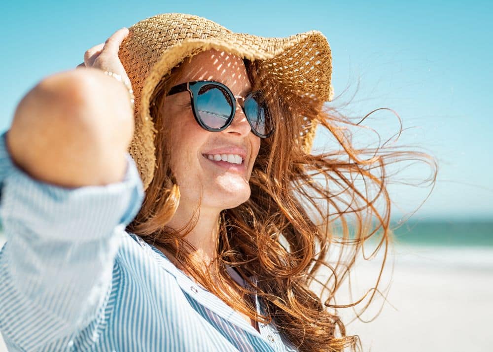 Woman wearing a straw hat and sun glasses on a beach